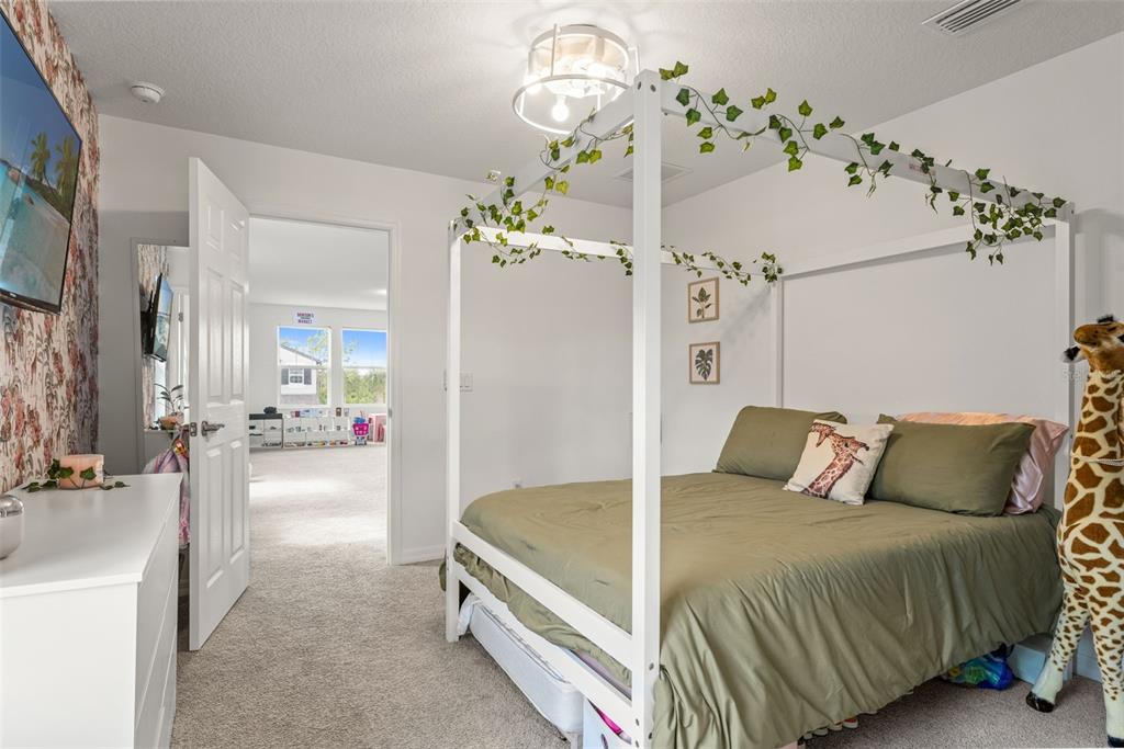 5945 Newberry Pnes Avenue Wesley Chapel, FL 33545 - Photo 39 of 55 a spacious bedroom with a bed mirror and chandelier