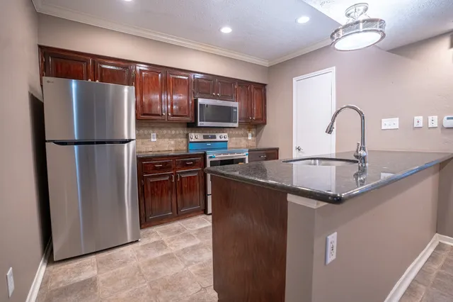 a kitchen with stainless steel appliances granite countertop a refrigerator a sink and a stove