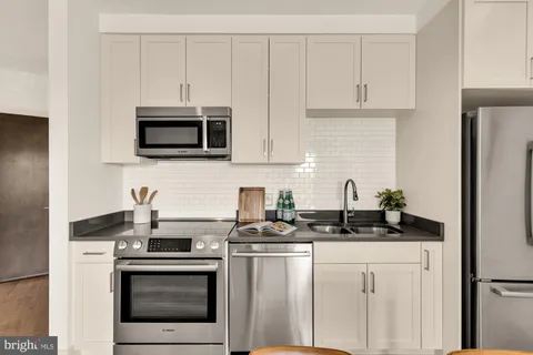 a kitchen with white cabinets and stainless steel appliances