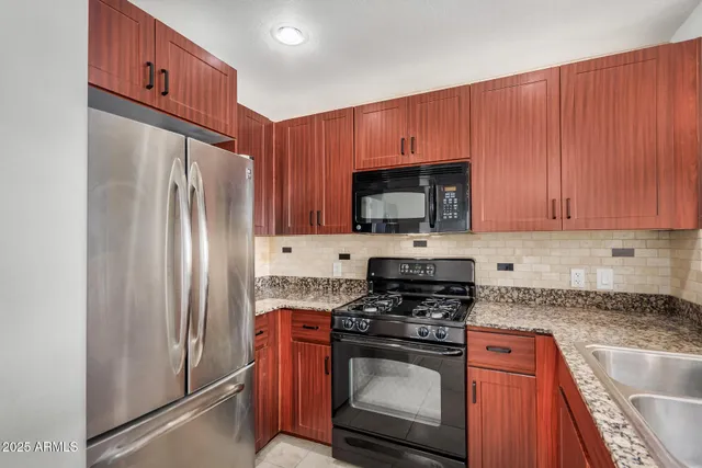 a kitchen with granite countertop a refrigerator stove and microwave