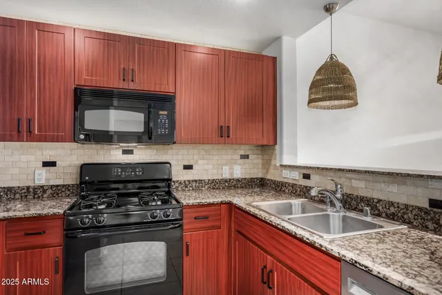 a kitchen with granite countertop a sink a stove and a microwave
