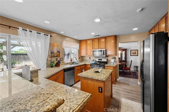 a kitchen with stainless steel appliances a dining table chairs refrigerator and sink