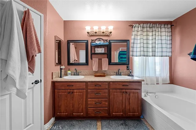 a bathroom with a sink double vanity granite tub shower and a mirror