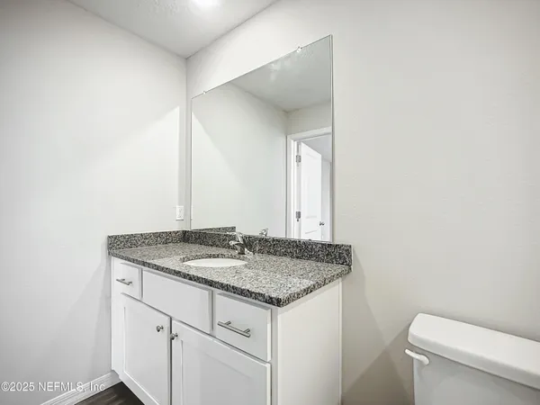 a bathroom with a granite countertop sink and a toilet