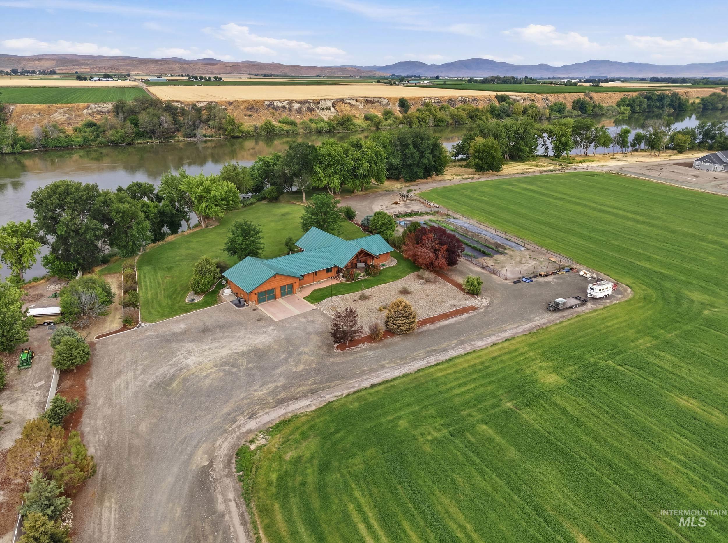 339 Airport Road Weiser, ID 83672 - Photo 37 of 49 Expansive property featuring a riverfront setting, large green fields, a substantial residence with a green roof, and a gravel driveway