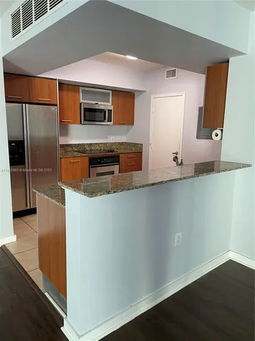 a kitchen with stainless steel appliances granite countertop a refrigerator and a stove
