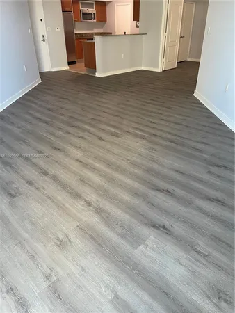a view of a sink and an empty room with wooden floor