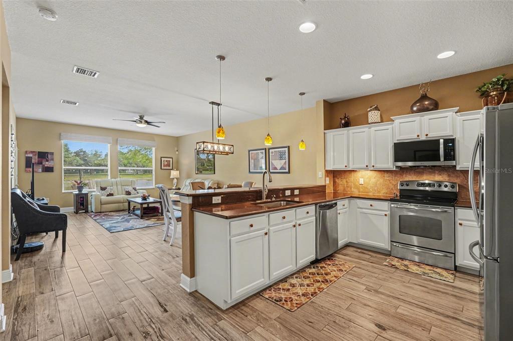 2134 Barracuda Court Holiday, FL 34691 - Photo 12 of 36 a kitchen with stainless steel appliances granite countertop a stove top oven a sink dishwasher a dining table and chairs with wooden floor