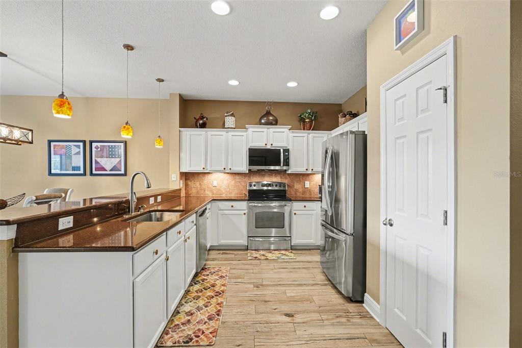 2134 Barracuda Court Holiday, FL 34691 - Photo 13 of 36 a kitchen with stainless steel appliances granite countertop a refrigerator a sink dishwasher a stove and white cabinets with wooden floor