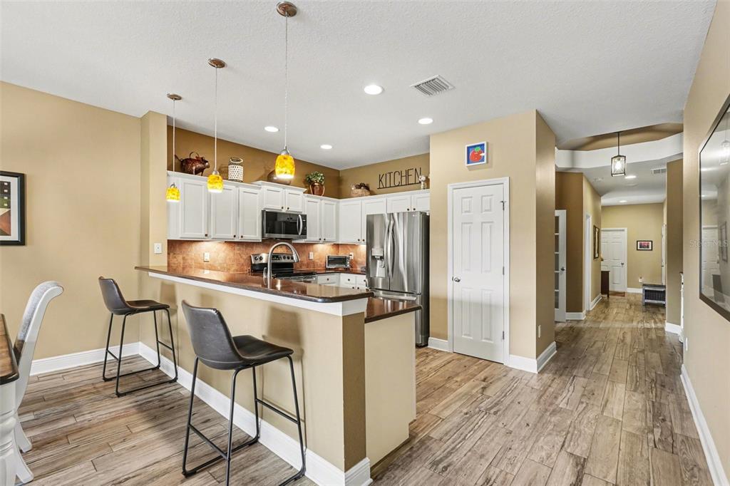 2134 Barracuda Court Holiday, FL 34691 - Photo 15 of 36 a kitchen with stainless steel appliances kitchen island granite countertop a refrigerator a stove a sink dishwasher and a dining table with wooden floor