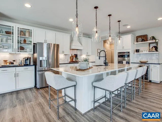 a kitchen with stainless steel appliances kitchen island granite countertop a refrigerator a stove a kitchen island with a dining table and chairs