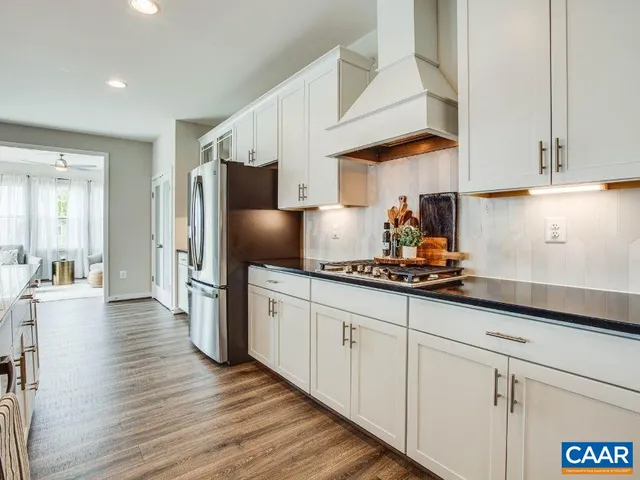 a kitchen with stainless steel appliances a sink dishwasher a refrigerator and cabinets with wooden floor