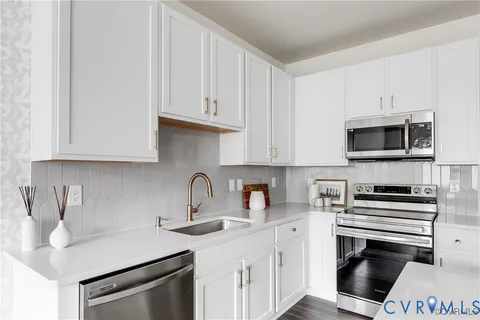a kitchen with stainless steel appliances a sink stove and white cabinets