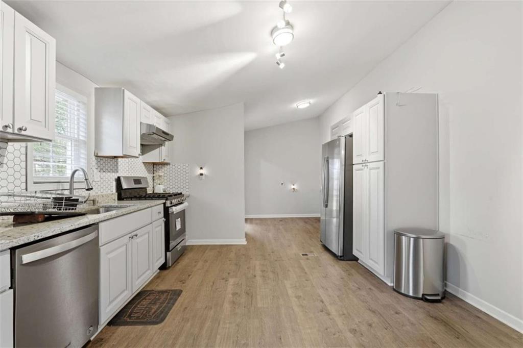 1295 Double Bridges Road Winder, GA 30680 - Photo 11 of 59 a kitchen with stainless steel appliances granite countertop a refrigerator a sink dishwasher a stove and white countertops with wooden floor