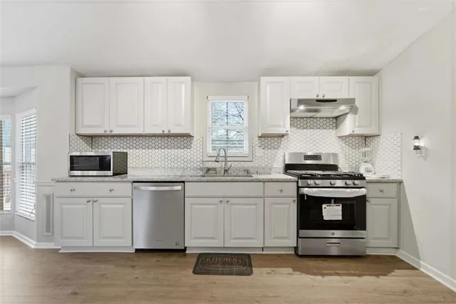 a kitchen with granite countertop white cabinets and white appliances