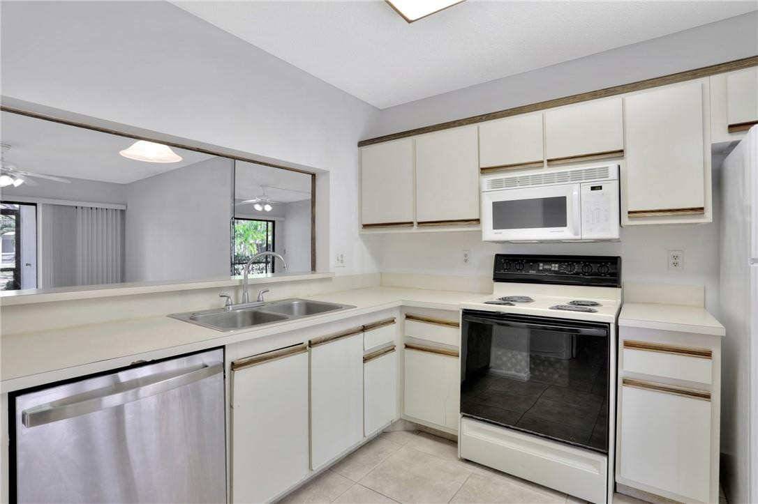 3939 Northeast 5th Avenue, Unit F104 Boca Raton, FL 33431 - Photo 14 of 34 a kitchen with white cabinets sink and stove
