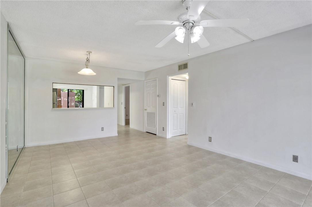 3939 Northeast 5th Avenue, Unit F104 Boca Raton, FL 33431 - Photo 26 of 34 an empty room with chandelier fan and windows