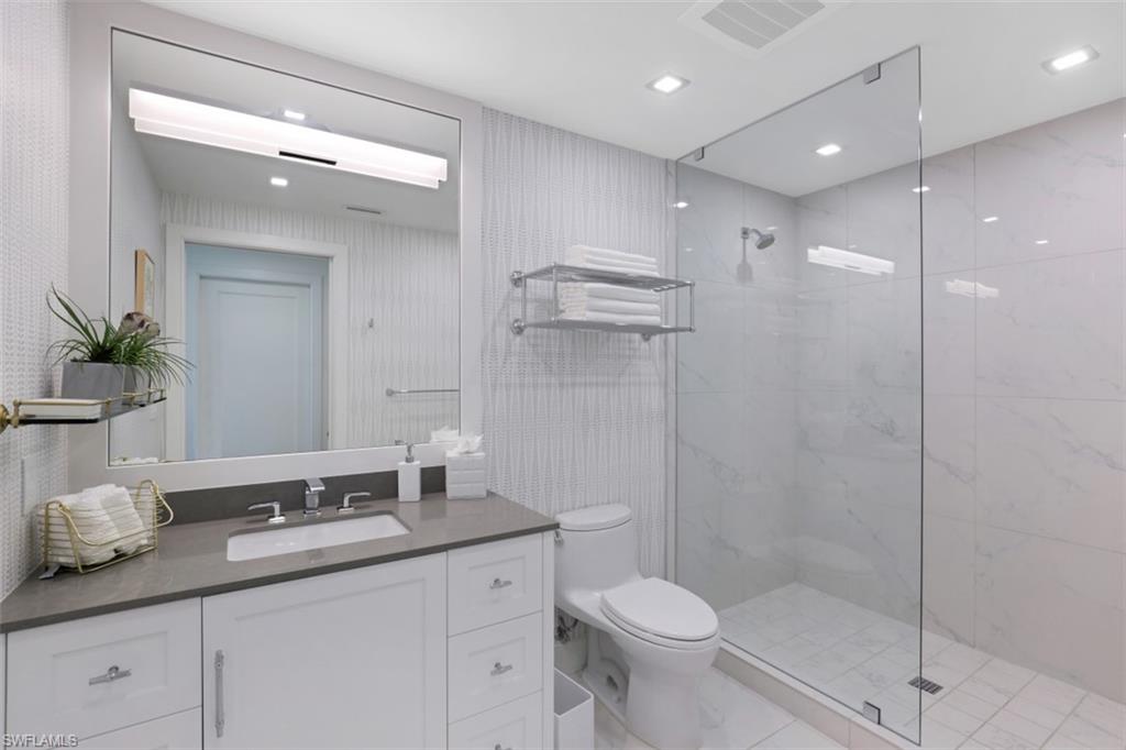13915 Old Coast Road, Unit 1601 Naples, FL 34110 - Photo 21 of 37 a bathroom with a granite countertop sink a toilet and shower