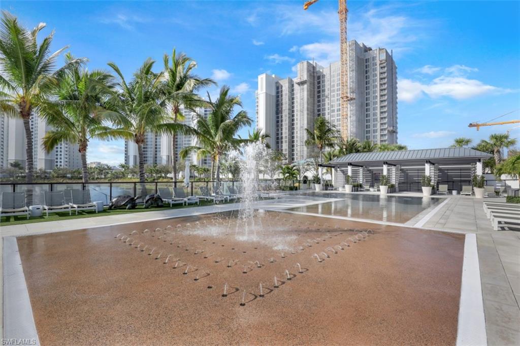 13915 Old Coast Road, Unit 1601 Naples, FL 34110 - Photo 28 of 37 a view of a swimming pool with a lawn chairs and palm tree