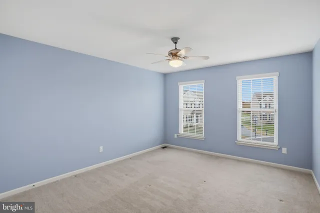 an empty room with windows and ceiling fan view