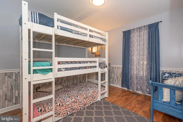 a view of an empty room with wooden floor and windows