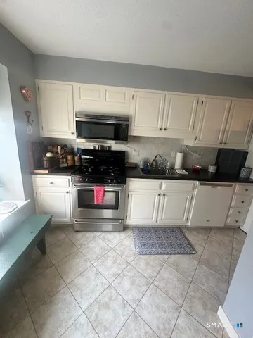 a kitchen with granite countertop a sink stove and cabinets