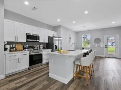 a kitchen with a dining table wooden floor and stainless steel appliances