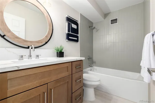 a bathroom with a granite countertop sink a toilet and a mirror