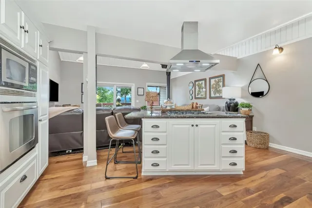 a kitchen with stainless steel appliances white cabinets and wooden floor
