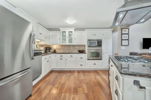 a kitchen with stainless steel appliances granite countertop a refrigerator sink and white cabinets