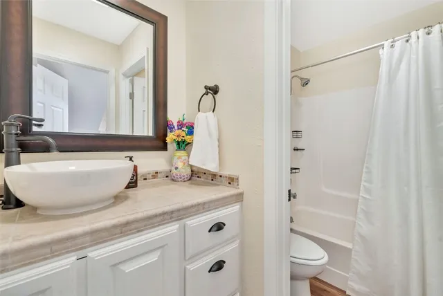 a bathroom with a granite countertop sink a toilet and shower