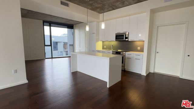 a kitchen with stainless steel appliances granite countertop a refrigerator a stove and a wooden floors