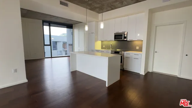 a kitchen with stainless steel appliances granite countertop a refrigerator a stove and a wooden floors