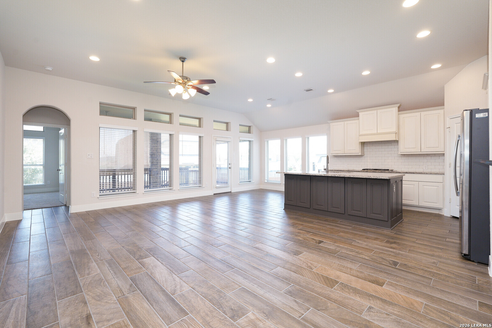 a view of an empty room with kitchen and window