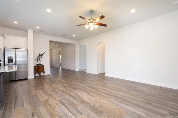 a view of an empty room with wooden floor and a ceiling fan