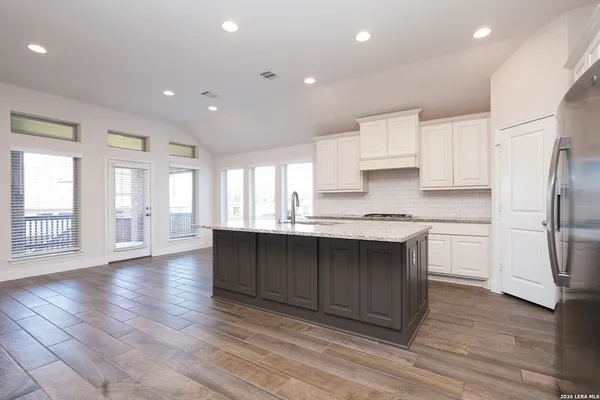 a kitchen with stainless steel appliances granite countertop a refrigerator a sink dishwasher and a stove with wooden floor