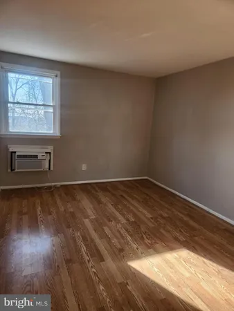 a view of an empty room and wooden floor and a window
