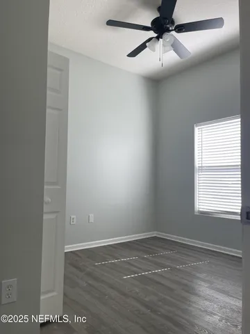 an empty room with a window and a ceiling fan