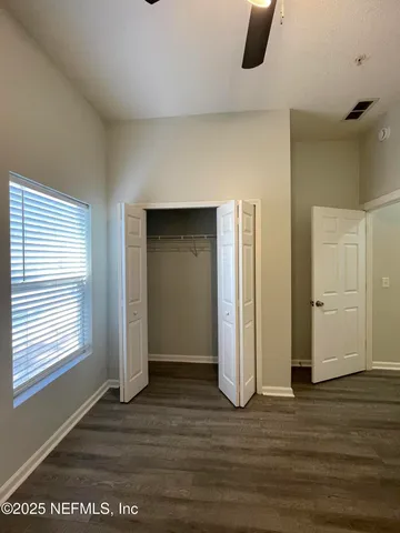 a view of an empty room with wooden floor and windows