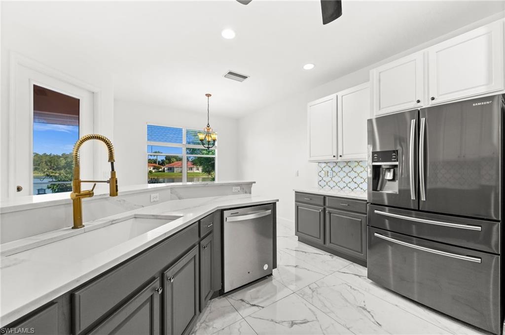 3972 Ruxton Road Naples, FL 34116 - Photo 10 of 41 a kitchen with stainless steel appliances kitchen island granite countertop a sink and dishwasher a refrigerator with wooden cabinets