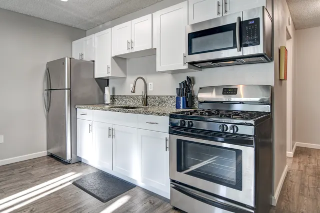 a kitchen with stainless steel appliances granite countertop a stove microwave and sink