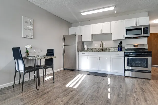 a kitchen with granite countertop a refrigerator stove and microwave