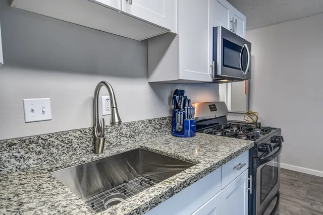 a kitchen with granite countertop a sink stainless steel appliances and cabinets