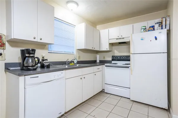a kitchen with granite countertop a white refrigerator oven a sink and cabinets