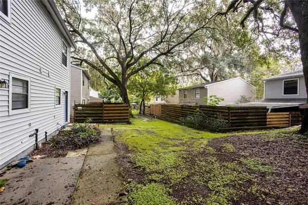 a backyard of a house with barbeque oven and large trees