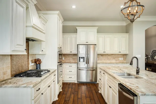 a large kitchen with stainless steel appliances granite countertop a lot of counter space and wooden floors