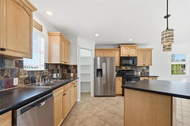 a kitchen with stainless steel appliances cabinets a sink and a large window