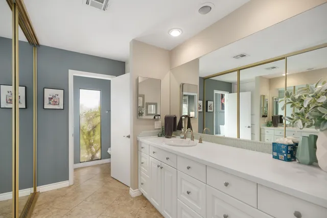 a spacious bathroom with double vanity a mirror and shower