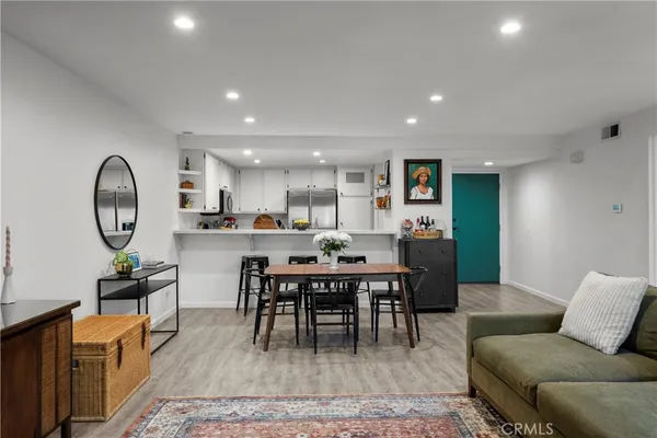 a living room with furniture a rug kitchen view and a window