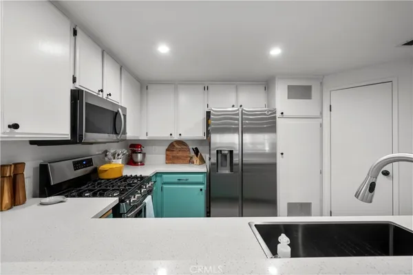 a kitchen with stainless steel appliances kitchen island granite countertop a refrigerator and a sink